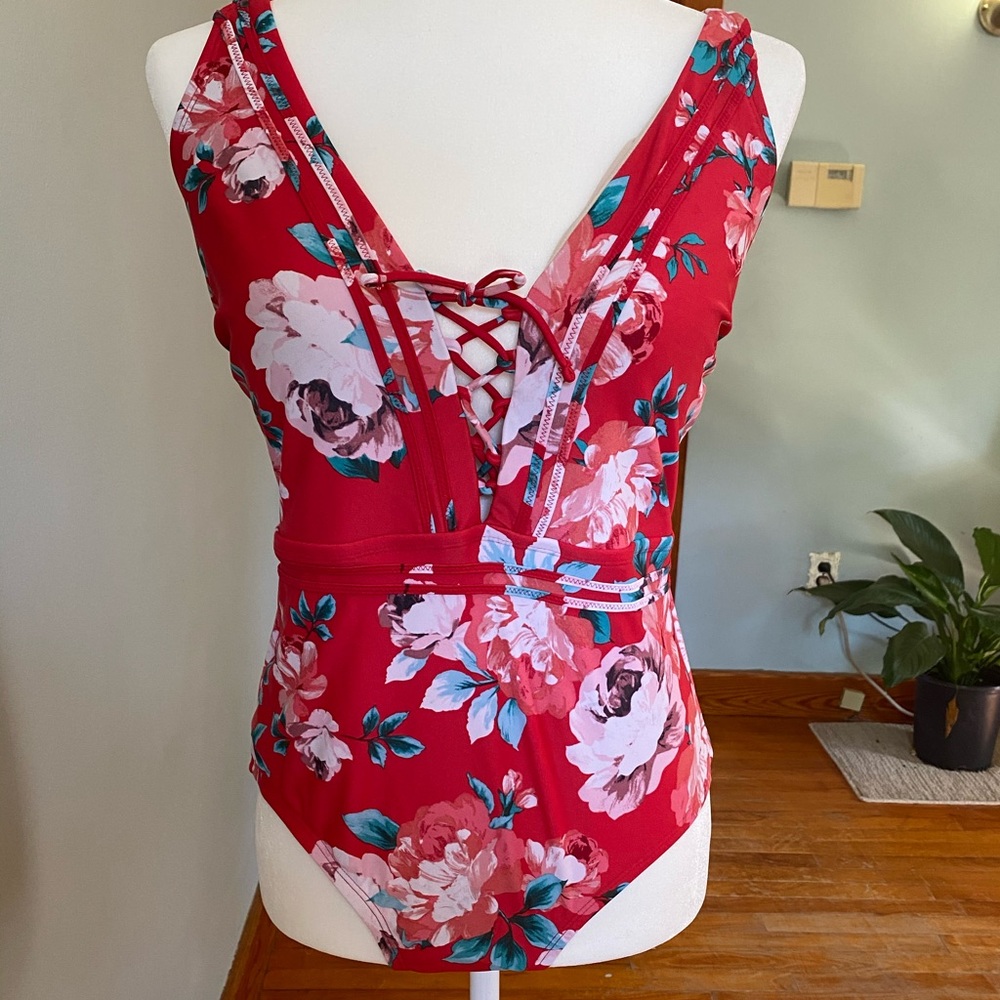 One piece suit in red with floral accents,…